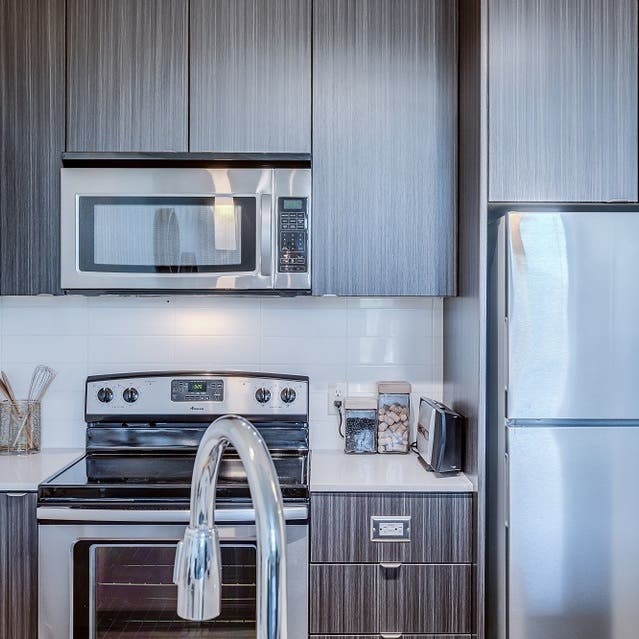 Osprey Apartments - kitchen with large island, dark cabinets, white countertops, and stainless steel appliances