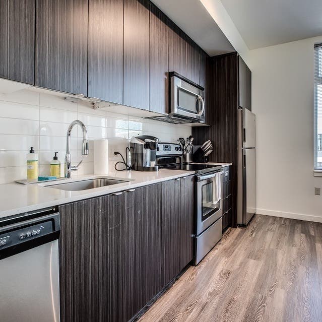 Osprey Apartments - kitchen with dark cabinets, white countertops, and stainless steel appliances