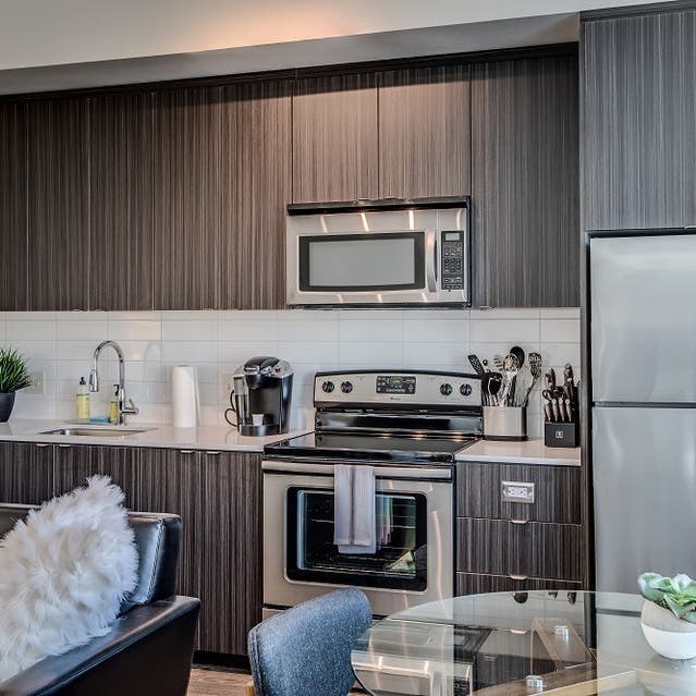 Osprey Apartments - kitchen with dark cabinets, white countertops, and stainless steel appliances