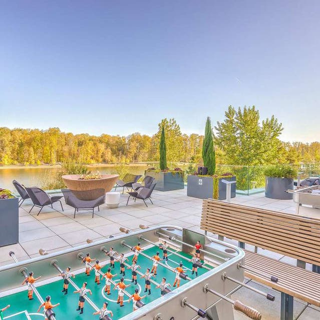 Osprey Apartments - river terrace with outdoor seating, fire pit, and foosball table